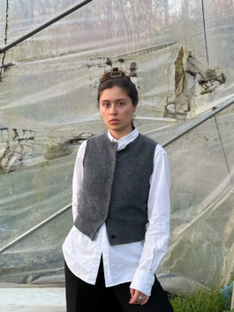 Portrait der Künstlerin Louisa Raspe für die Biennale für Freiburg 3, 2025. Sie trägt ein weißes Hemd und ein graue Weste. 